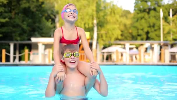 Little girl sits on shoulders of brother — Stock Video