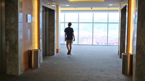 Pojken går i hall med dörrar av hissar — Stockvideo