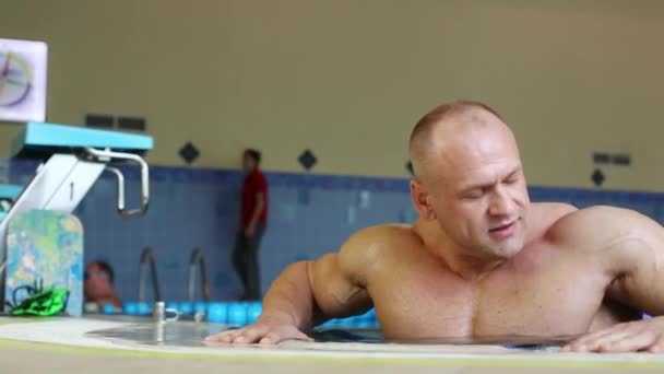 Bodybuilder in zuivere binnenzwembad — Stockvideo