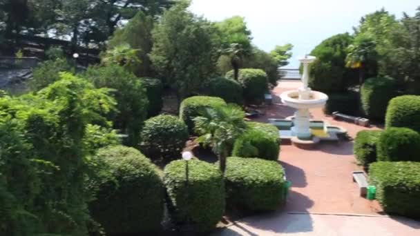 Сад с фонтаном, лестница, кусты и вид на море — стоковое видео