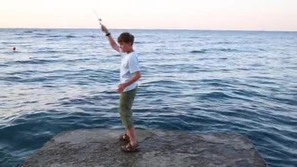 Boy with rod fishing in sea — Stock Video