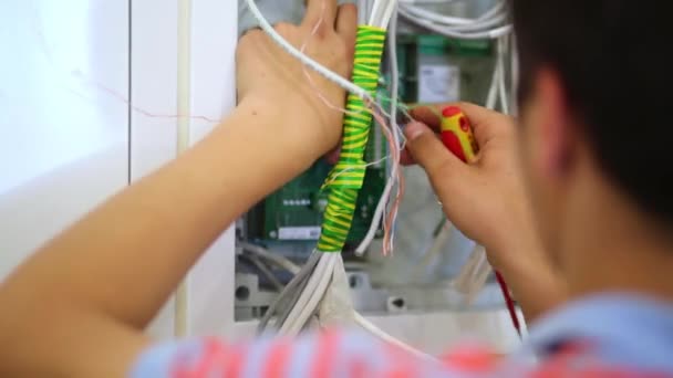 Workman empaca cables en caja de distribución durante el montaje — Vídeo de stock