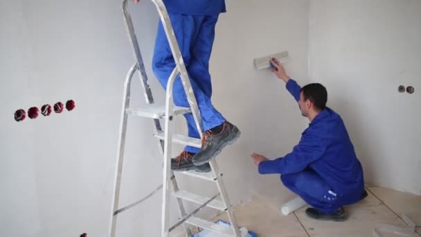 Man glad fiberglas, in de buurt van een man op een ladder uitstrijkjes lijm — Stockvideo