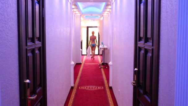 Повернення жінки в купальнику йде в коридор готелю — стокове відео