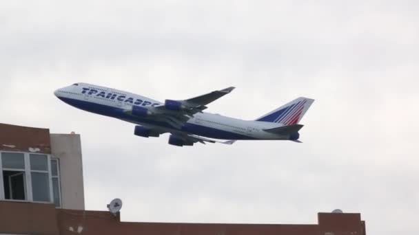 Avión Transaero vuela en el cielo sobre edificios — Vídeo de stock