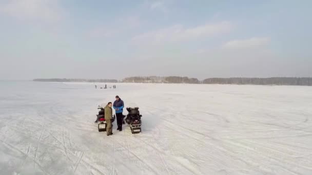 Twee mannen staan in de buurt van sneeuw mobielen — Stockvideo