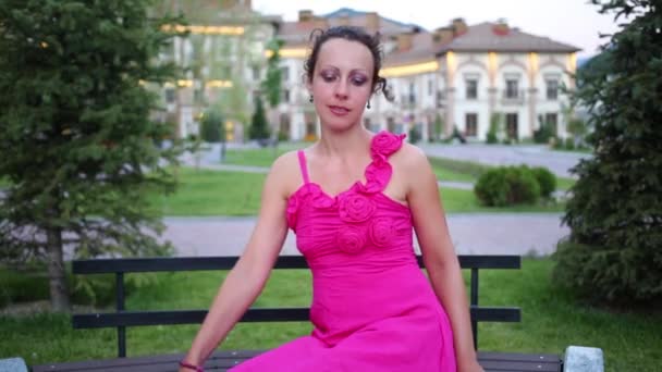 Femme en robe s'assoit sur le banc — Video