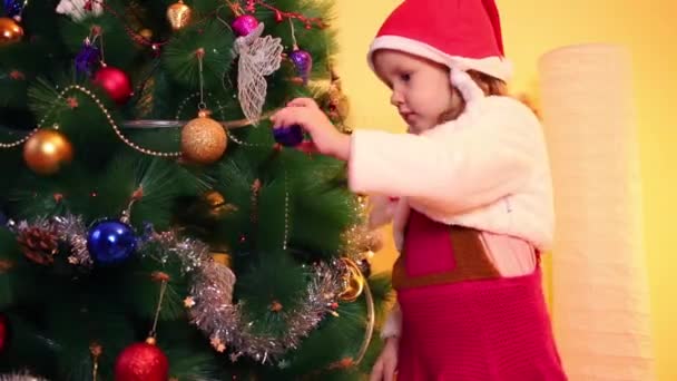 Little girl decorates christmas tree — Stock Video