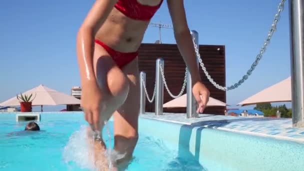 Мальчик плавает, девочка выходит из бассейна — стоковое видео