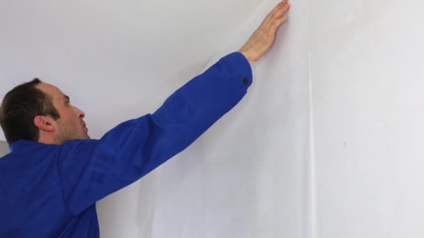 Ein Mann klebt Kleidungsstücke an die Glasfaserwand — Stockvideo