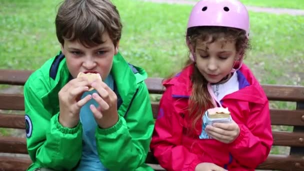 Мальчик и девочка едят мороженое — стоковое видео