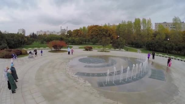 Rodiče s dětmi sledovat suché fontána — Stock video