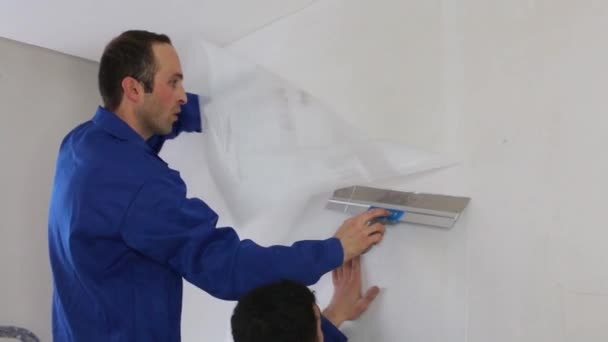 Arbeiter glätten Glasfaserplatten an der Wand mit einem Spachtel — Stockvideo