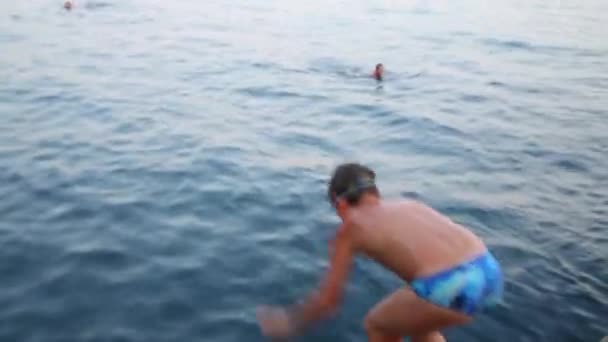 Ein kleiner Junge mit Brille springt ins Wasser — Stockvideo