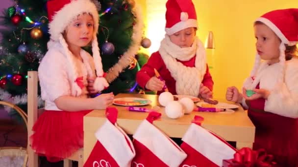 Barn måla cookies nära julgran — Stockvideo