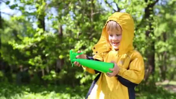 Chlapec v žlutá pláštěnka hraje s rozprašovačem — Stock video