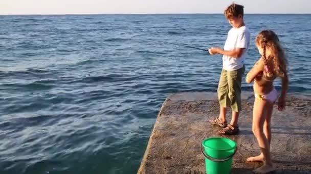 Niño con caña de pescar en el mar en muelle — Vídeos de Stock