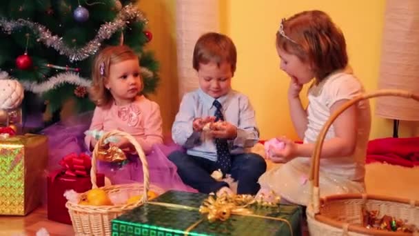 Kleine meisjes en jongen in de buurt van de kerstboom — Stockvideo