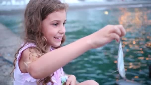 Menina está olhando para o peixe pequeno capturado — Vídeo de Stock