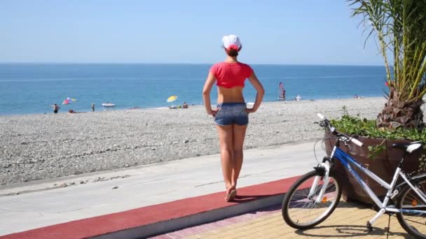 Woman in shorts looking at stony beach — Stock Video