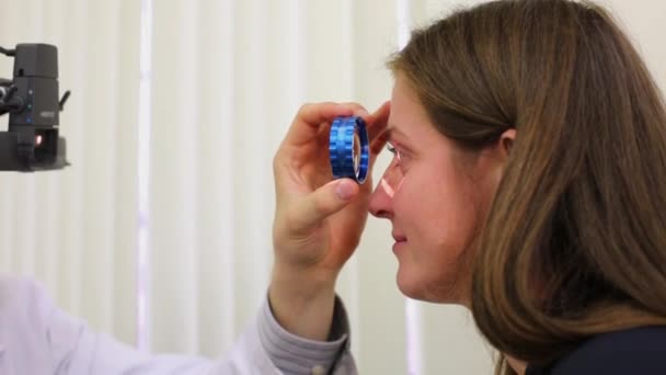 Oftalmólogo examina ojo de mujer a través de oftalmoscopio — Vídeos de Stock