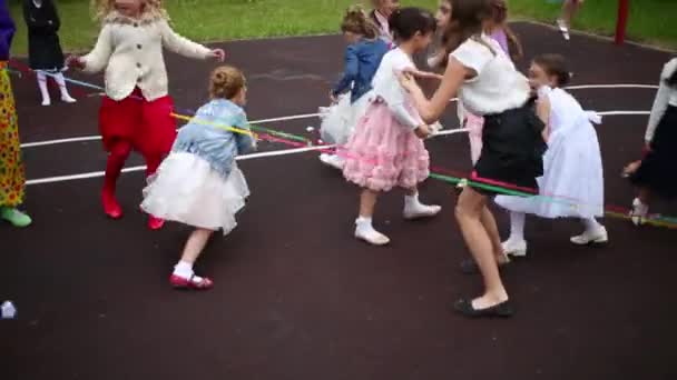 Kinderen gooien papier over touw op speelplaats — Stockvideo