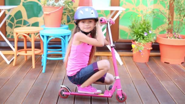 Girl in helmet sitting on floor with scooter — Stock Video