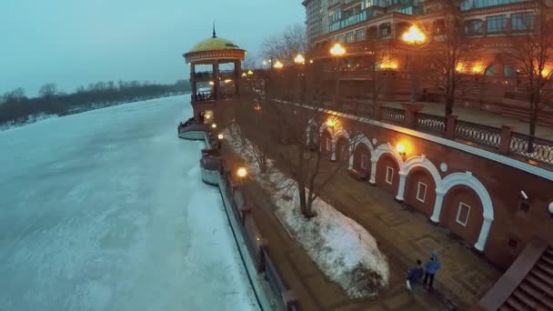 Люди ходят по набережной возле реки — стоковое видео