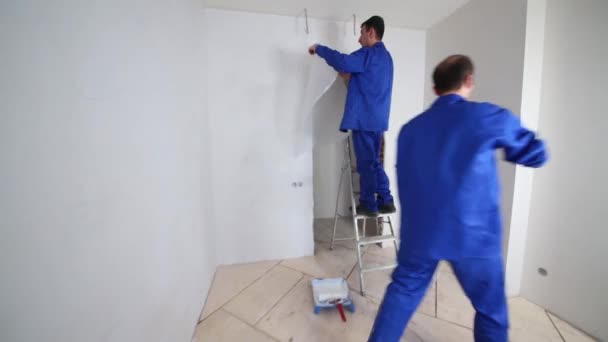 Werknemer lijm glasvezel blad aan de muur boven de deuropening — Stockvideo