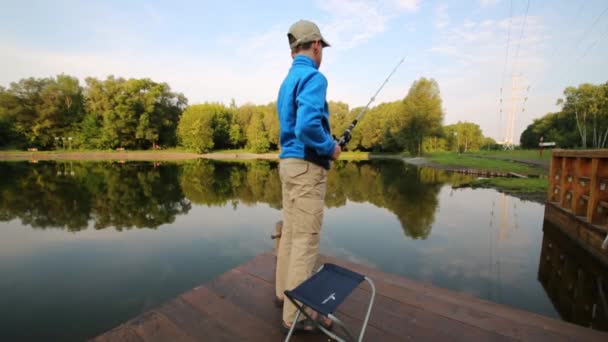 Boy stands near lake with fishing rod — Stock Video