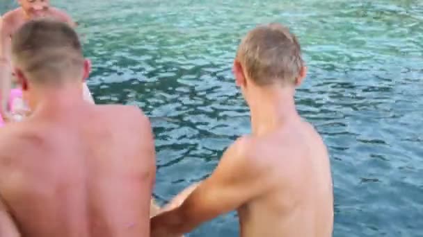 Männer werfen einen anderen Mann ins Wasser. — Stockvideo