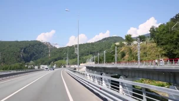 Движение по дороге рядом с железной дорогой среди гор — стоковое видео