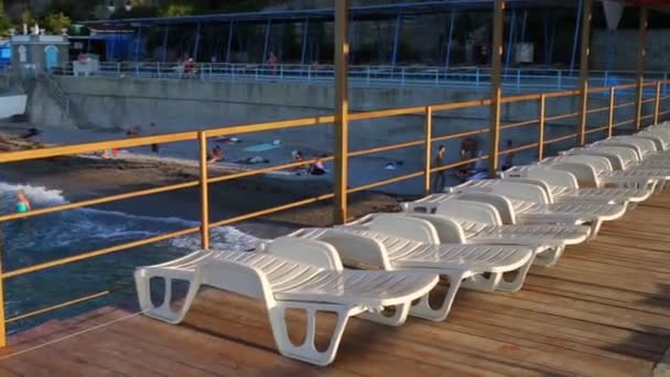 Deck chairs on pier and resting people at evening — Stock Video