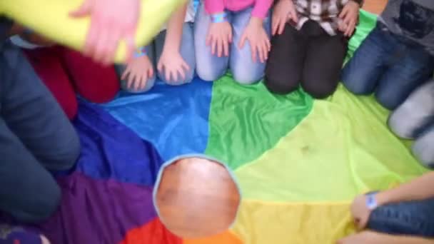 I bambini giocano seduti sul pavimento all'anello di stoffa arcobaleno — Video Stock