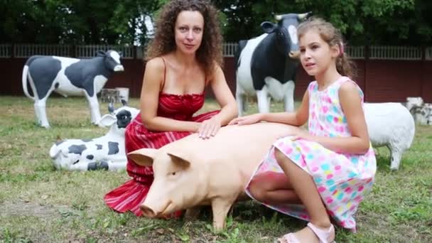 Mère et fille assis près de cochon artificiel — Video