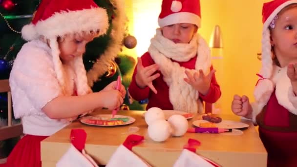 Kleine Mädchen und Jungen in Weihnachtsmützen — Stockvideo