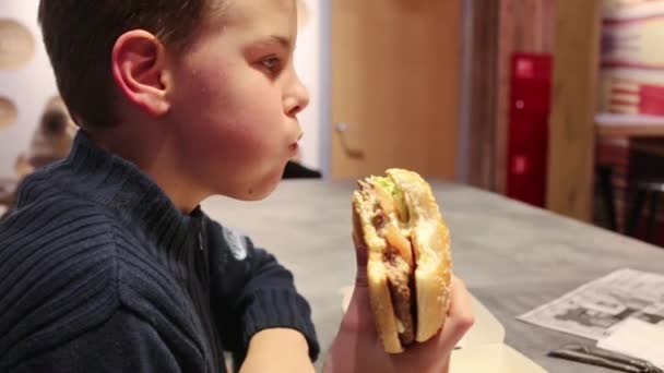 Kis fiú eszik nagy burger — Stock videók