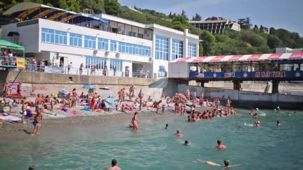 Mensen ontspannen op het strand in de buurt van pier — Stockvideo