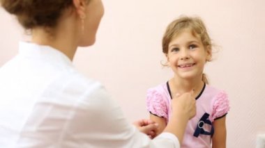 Kadın doktor termometre kızdan alır.