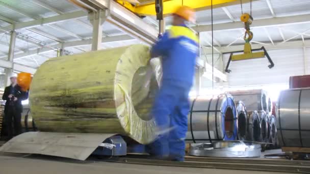 Workers remove packing from roll of metal — Stock Video