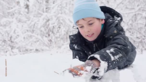 Ung pojke gör snöboll och kast — Stockvideo