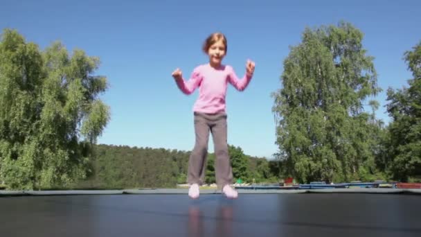 Маленька дівчинка стрибає на батуті — стокове відео