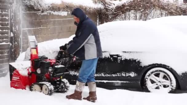 Чоловік прибирає сніг біля будинку — стокове відео