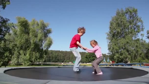 Niño con chica saltar en trampolín — Vídeos de Stock