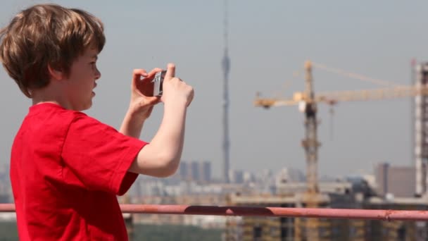 Garçon regarde et prend des photos de la maison — Video