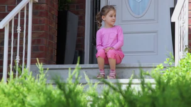 Маленькая девочка сидит на крыльце — стоковое видео
