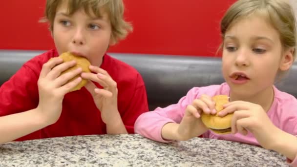 Boy with little girl eat hamburgers — Stock Video