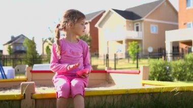 Küçük kız oturur ve kum ile çalış