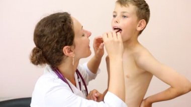 Kadın doktor çocuğun boğazını inceler