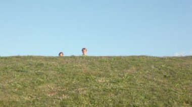 Oğlanla kız yakın çim tepenin arkasından koşmak